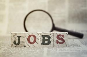 verweist auf: Stellenangebote das Wort JOBS auf Holzblöcke geschrieben vor einer Lupe auf einer Zeitung liegend (verweist auf: Stellenangebote)