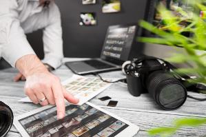 verweist auf: Pressefotos Mitarbeiterin/Journalistin wählt Fotos über ein iPad aus, Kamera liegt auf dem Tisch (verweist auf: Pressefotos)
