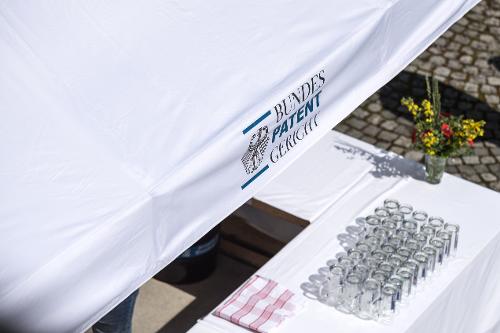 Blick zum Ausschank mit Gläsern und Logo "Bundespatentgericht" auf einem Pavillon Blick zum Ausschank mit Gläsern und Logo "Bundespatentgericht" auf einem Pavillon
